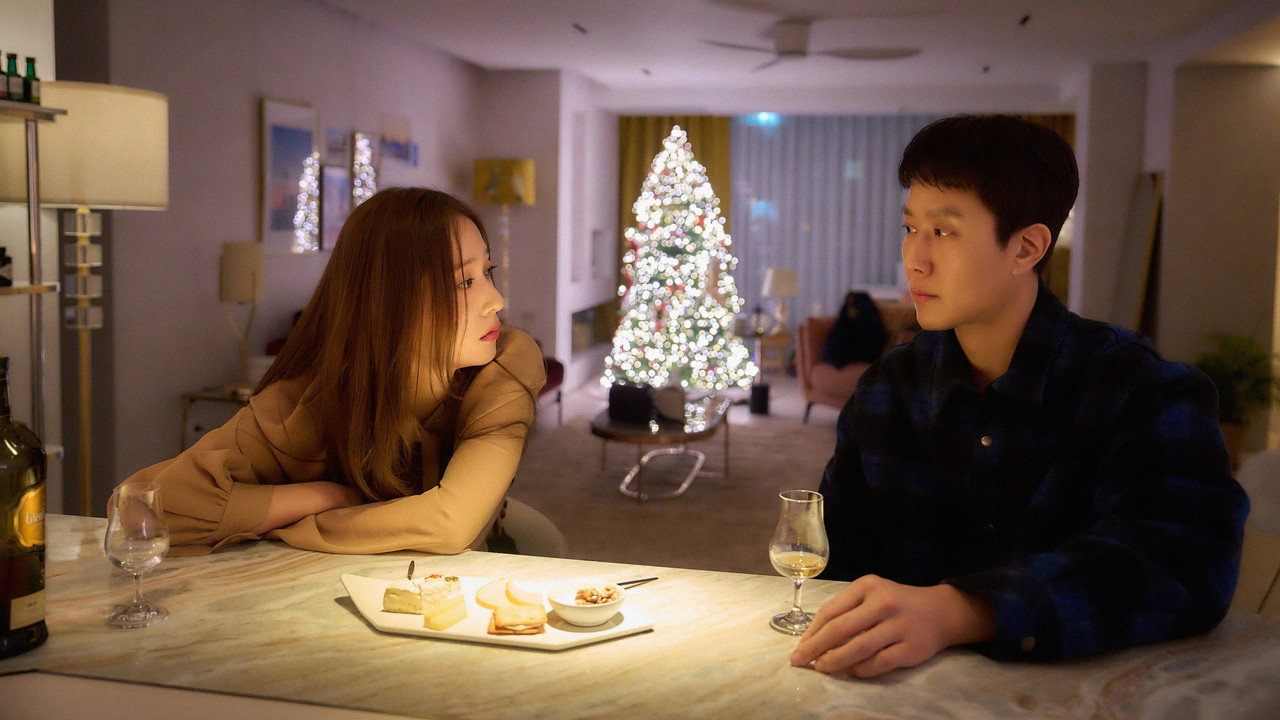 트리 조명이 있는 거실 식탁에 마주 앉은 두 사람의 스틸