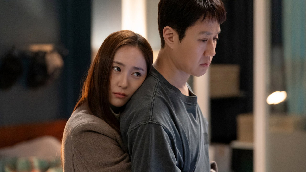 회색 티셔츠의 어깨에 베이지 코트를 입고 기댄 사람의 스틸